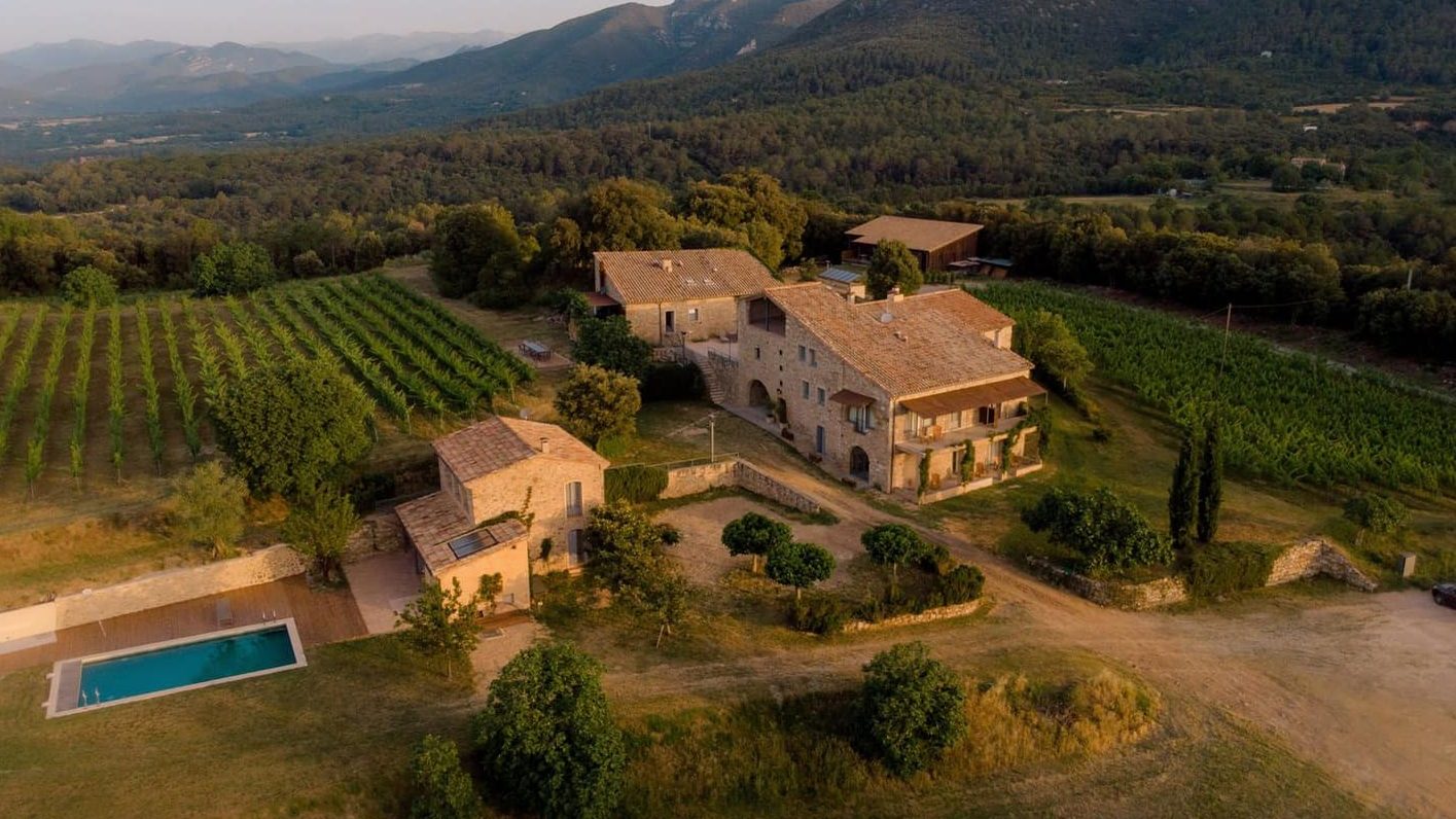 A stone country estate with a pool, surrounded by vineyards and woodland in Catalonia